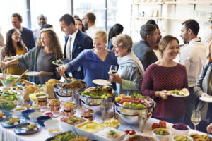 People enjoying at a catering event with lots of food.